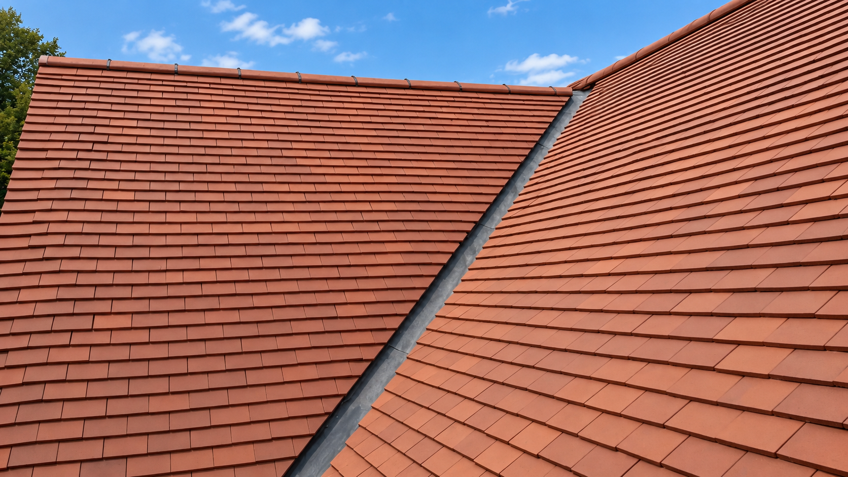 Terracotta tiled roof with a clean lead valley and mechanically fixed ridge tiles