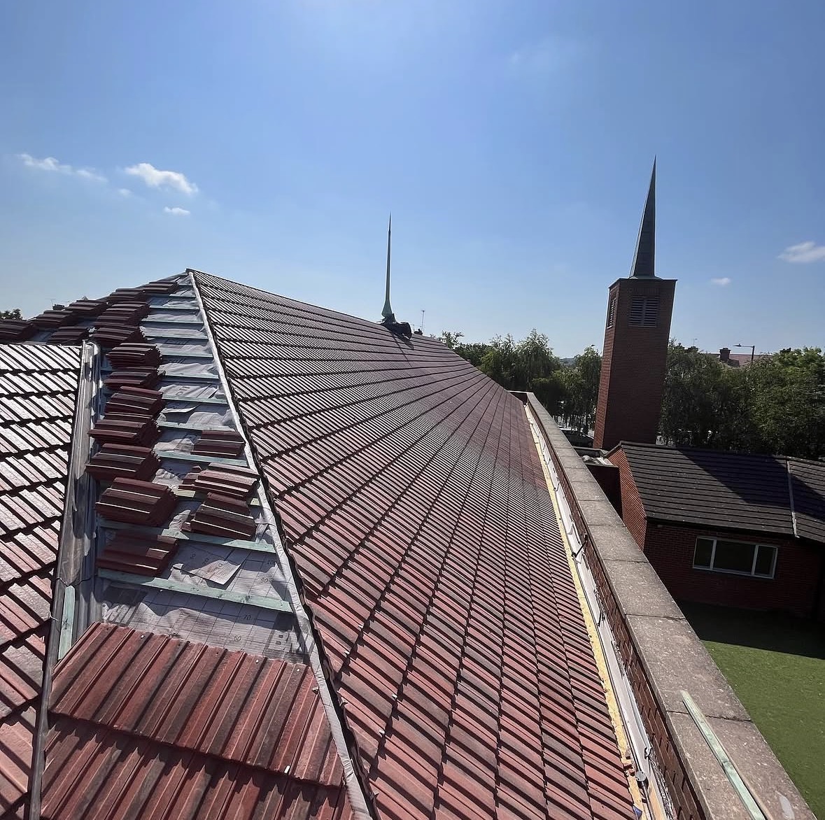 Tiled roof being renewed with tiles stacked beside the exposed hip