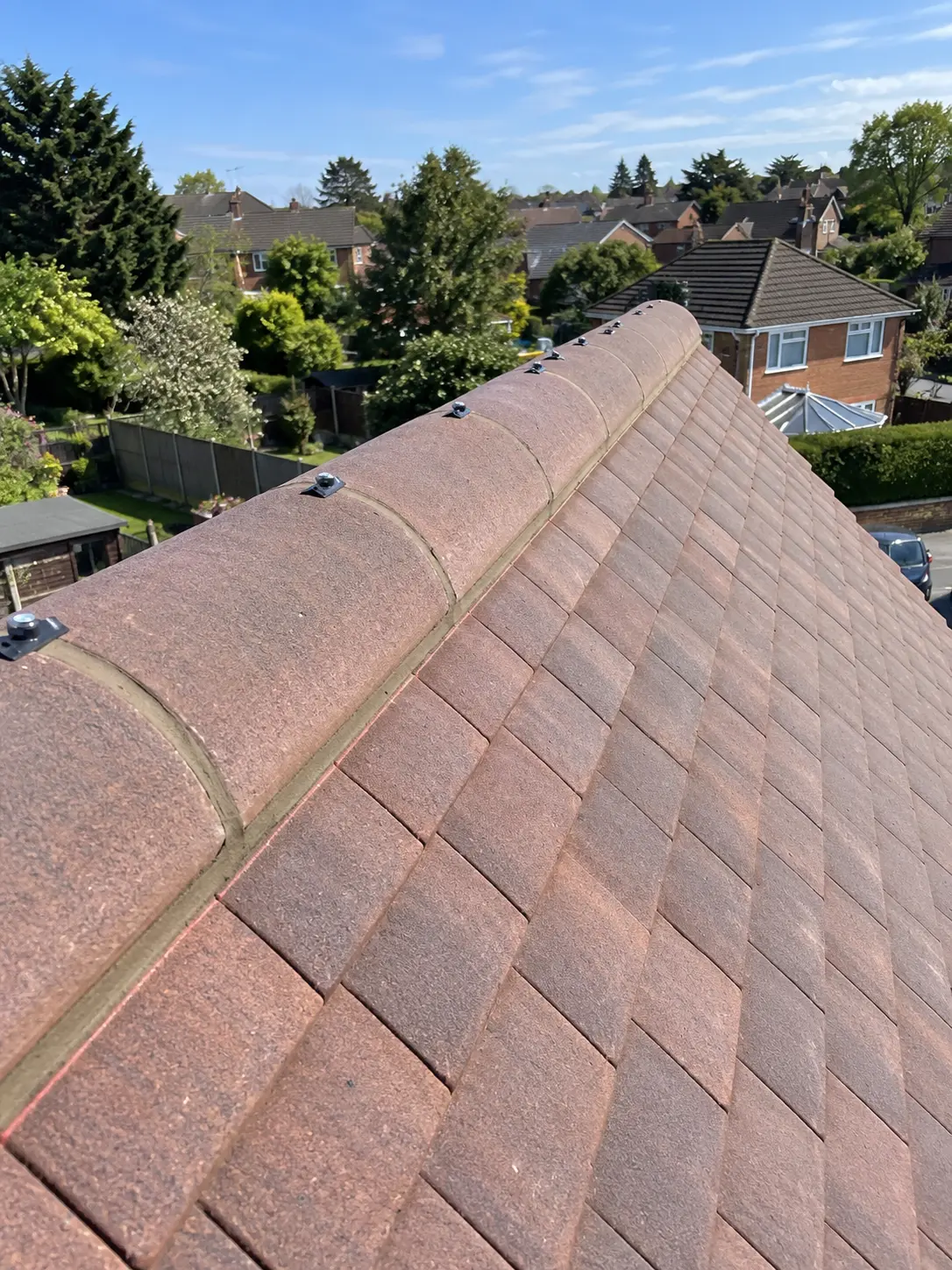 Half-round ridge tiles mechanically fixed along the ridge of a tiled roof