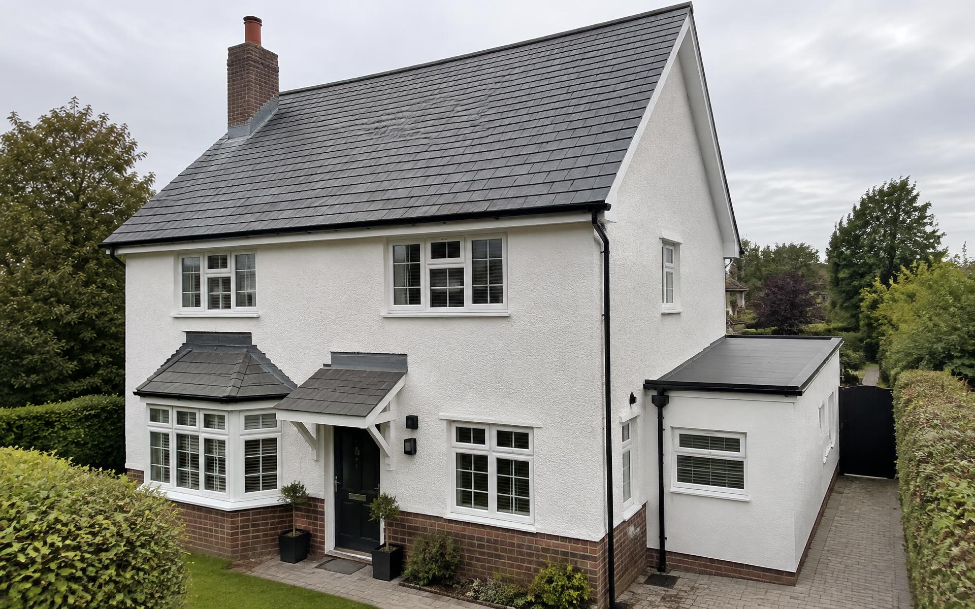 Detached house with a slate roof, chimney, bay window and flat-roof side extension