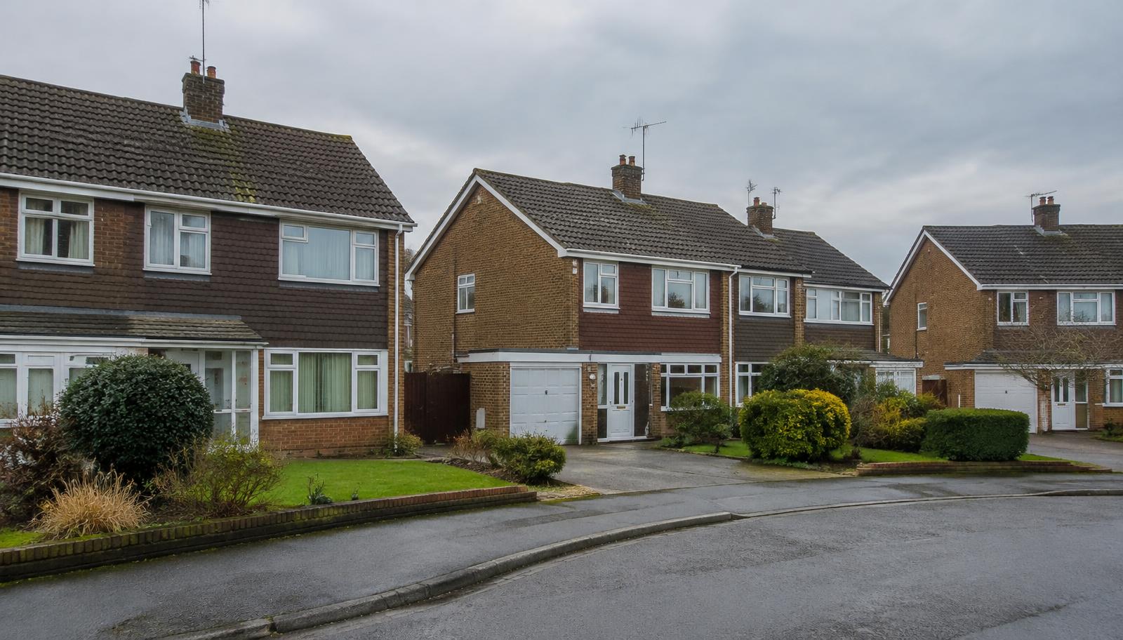 1960s and 1970s semi-detached houses with brown concrete interlocking roof tiles around a cul-de-sac